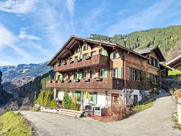 A traditional wooden chalet with balconies, a stone foundation, and a view of the surrounding mountains. - Chalet Auf dem Vogelstein by Interhome (Grindelwald)