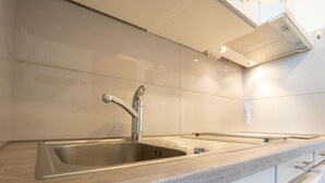 A modern kitchen with a stainless steel sink, a wooden countertop, and white cabinetry. - Chavière 832 by Interhome (Les Menuires)