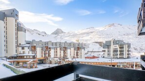 Une ville de montagne enneigée, avec des bâtiments modernes, dont un hôtel doté de balcons et offrant une vue sur les montagnes.