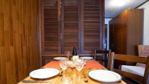 Une table à manger dressée avec des assiettes, des couverts et des verres, avec un lambris en bois et un lit en arrière-plan.