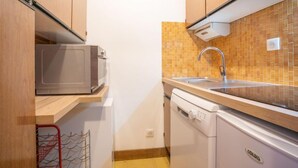 Une cuisine compacte équipée d’un four à micro-ondes, d’un évier et d’un lave-vaisselle.