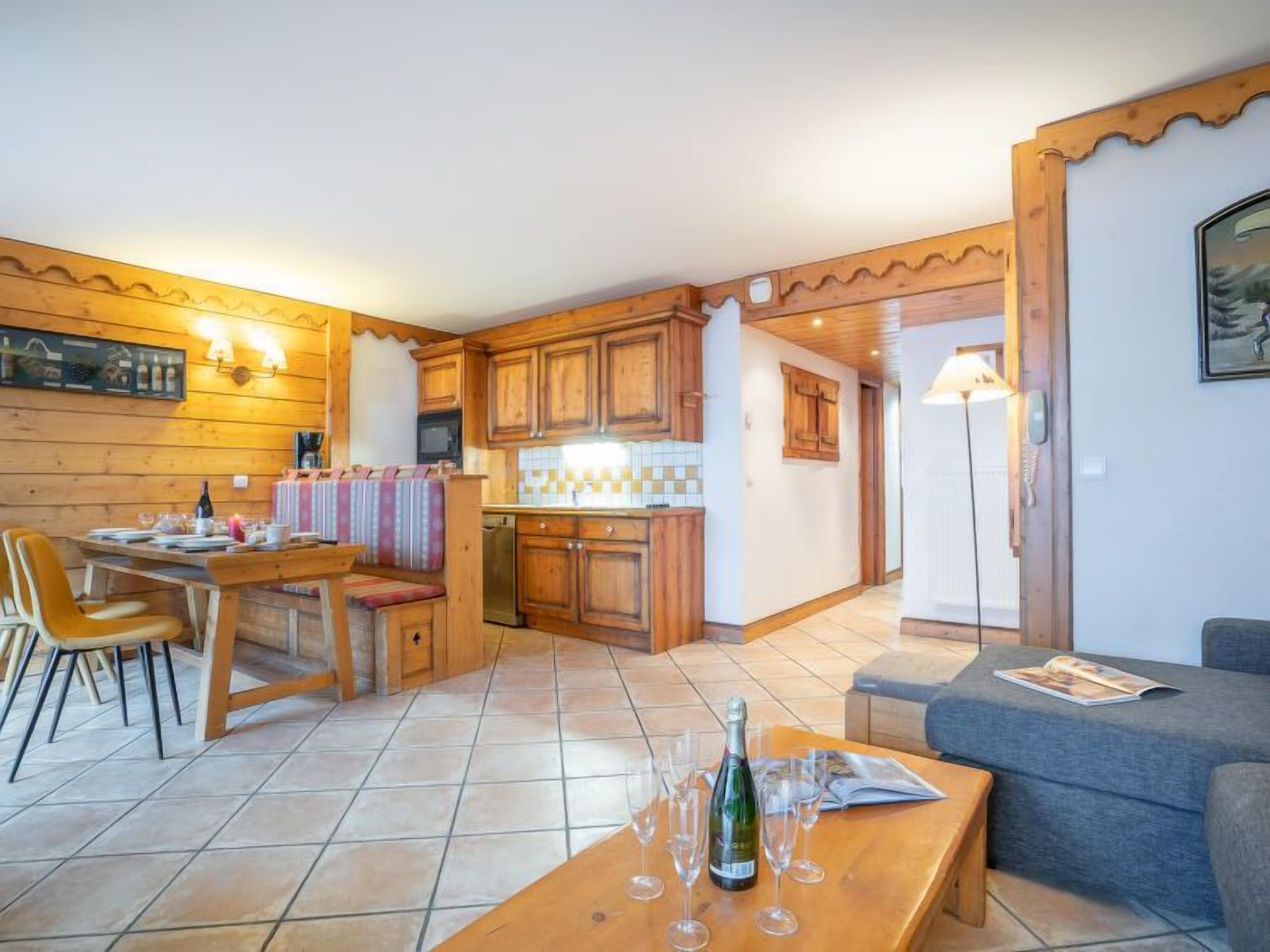 A cozy living room with a dining area, wooden cabinets, and a tiled floor.