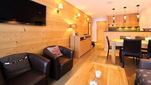 A modern interior with wooden walls, a flat-screen TV, leather sofas, a dining area, and a kitchen. - Les Hauts du Val Claret(Val Claret) by Interhome (Tignes)