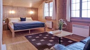 Ein Holzhüttenraum mit einem Bett, einem kleinen Tisch mit einer Pflanze und einem Fenster mit Vorhängen.