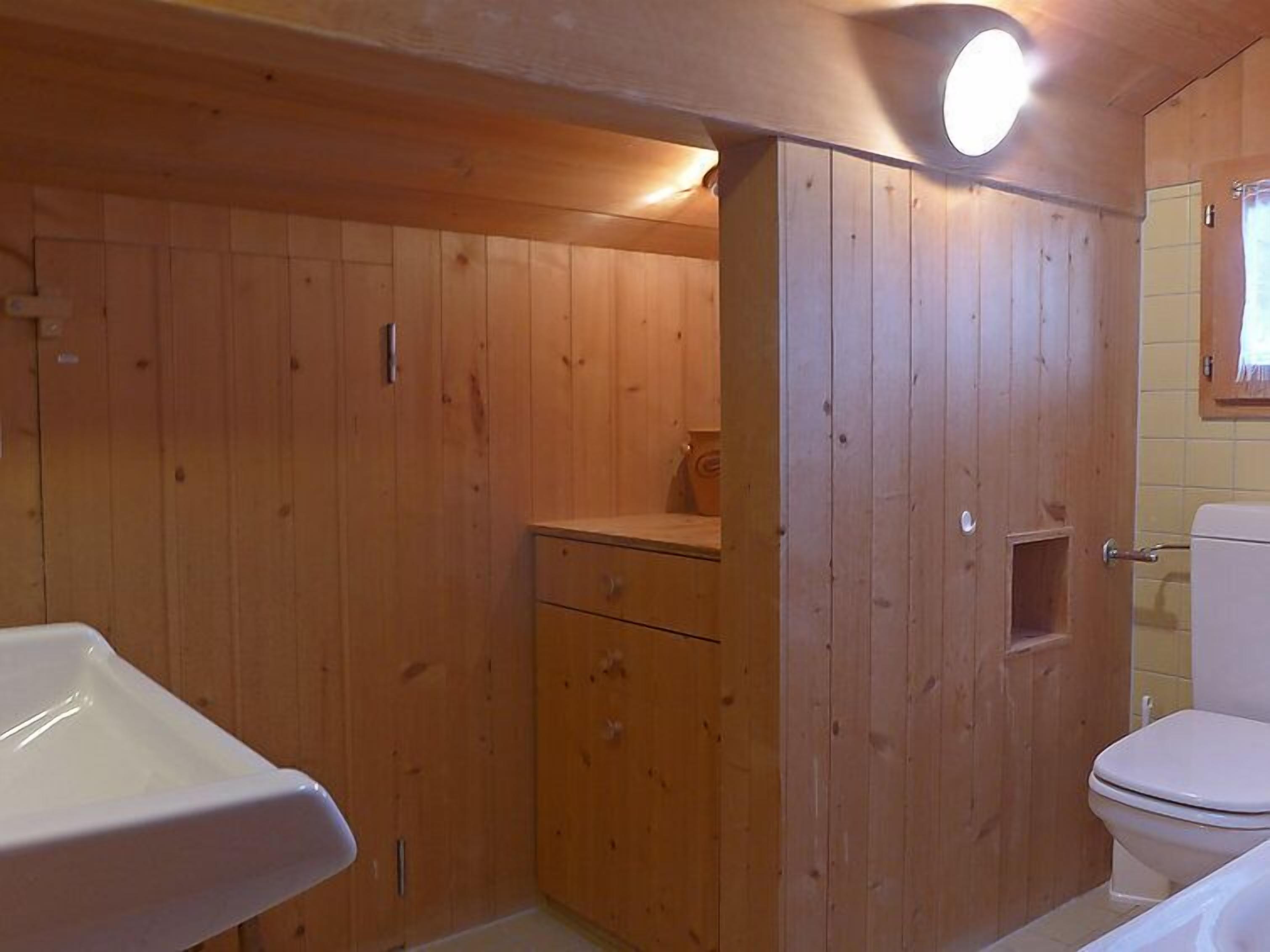 Un baño estilo cabaña de madera con lavamanos, inodoro y armario de madera.