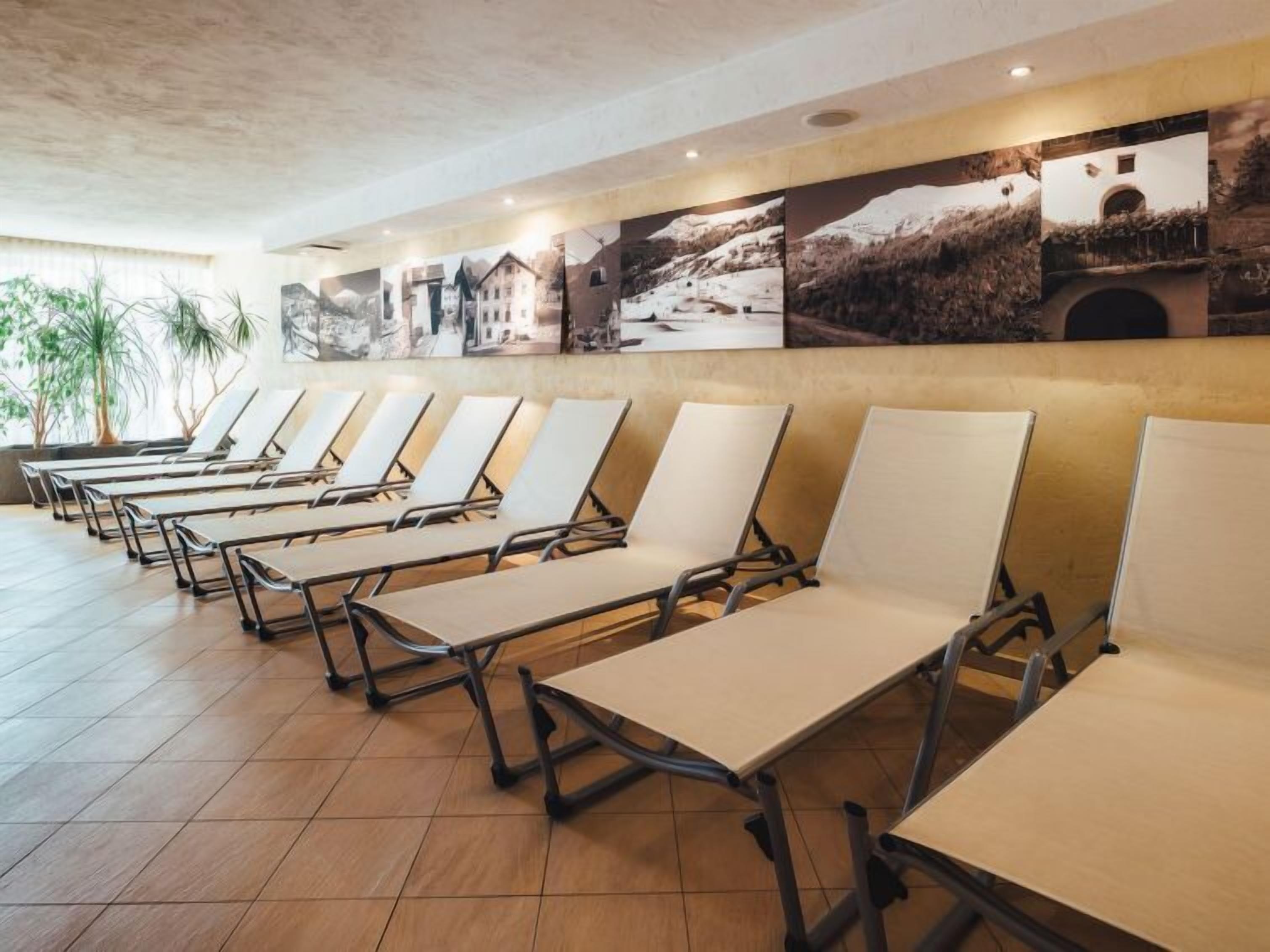 Un hall d’hôtel avec des rangées de chaises longues et un mur décoré de photographies de paysages.