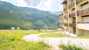A hotel with a mountain view, a dirt path leading to the entrance, and a balcony with wooden railings.