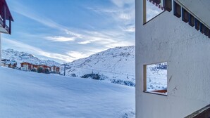A snow-covered landscape with a building featuring a window and a wooden railing.