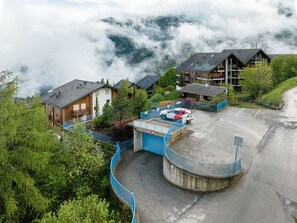 A mountainous area with a parking lot, buildings, and a blue fence.