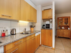 A kitchen with wooden cabinets, a granite countertop, a sink, a coffee maker, and a microwave.
