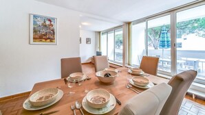 Comedor con una mesa grande dispuesta para seis personas, rodeada de sillas y vistas al exterior a través de amplios ventanales.