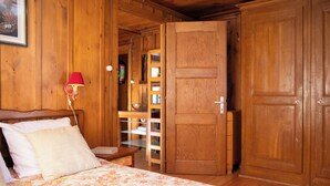 Una stanza in legno con un letto, una lampada rossa e un'uscita verso una zona cucina.