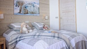 Een slaapkamer met een houten plafond, een groot schilderij van een ijsbeer, een bed met een gestreept dekbed en een teddybeer op de kussens.