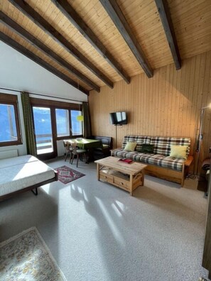 Relax in this inviting room with a sofa, dining area, and large windows offering a view of the outdoors.