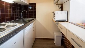 Una cocina compacta con estufa, lavaplatos, microondas y un pequeño basurero.