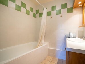 Une salle de bain équipée d’une baignoire, d’une douche et d’un lavabo, ainsi que de serviettes.