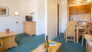 A compact living space with a kitchenette, a dining area, and a small TV on a wooden cabinet.