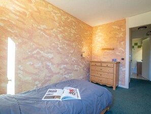 Une chambre à coucher comprenant un lit, une commode en bois et une porte donnant sur une salle de bain.