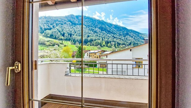 Un balcon offrant une vue sur un paysage montagneux et un bâtiment situé au loin.