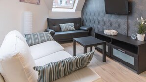 A modern living room with a sofa, a coffee table, and a TV on a stand.