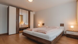 Un dormitorio moderno con una cama grande, suelo de madera y un armario con espejo.