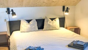 Une chambre à coucher avec un grand lit, deux lampes de chevet, une tête de lit sombre et un tapis à rayures.