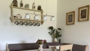 Ein Essbereich mit Holztisch und Stühlen, einer Hängelampe und Wandregalen mit Dekoration.