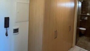 Ein Zimmer mit einem Holzschrank, einem weißen Wandtelefon und einer kleinen Steckdose.