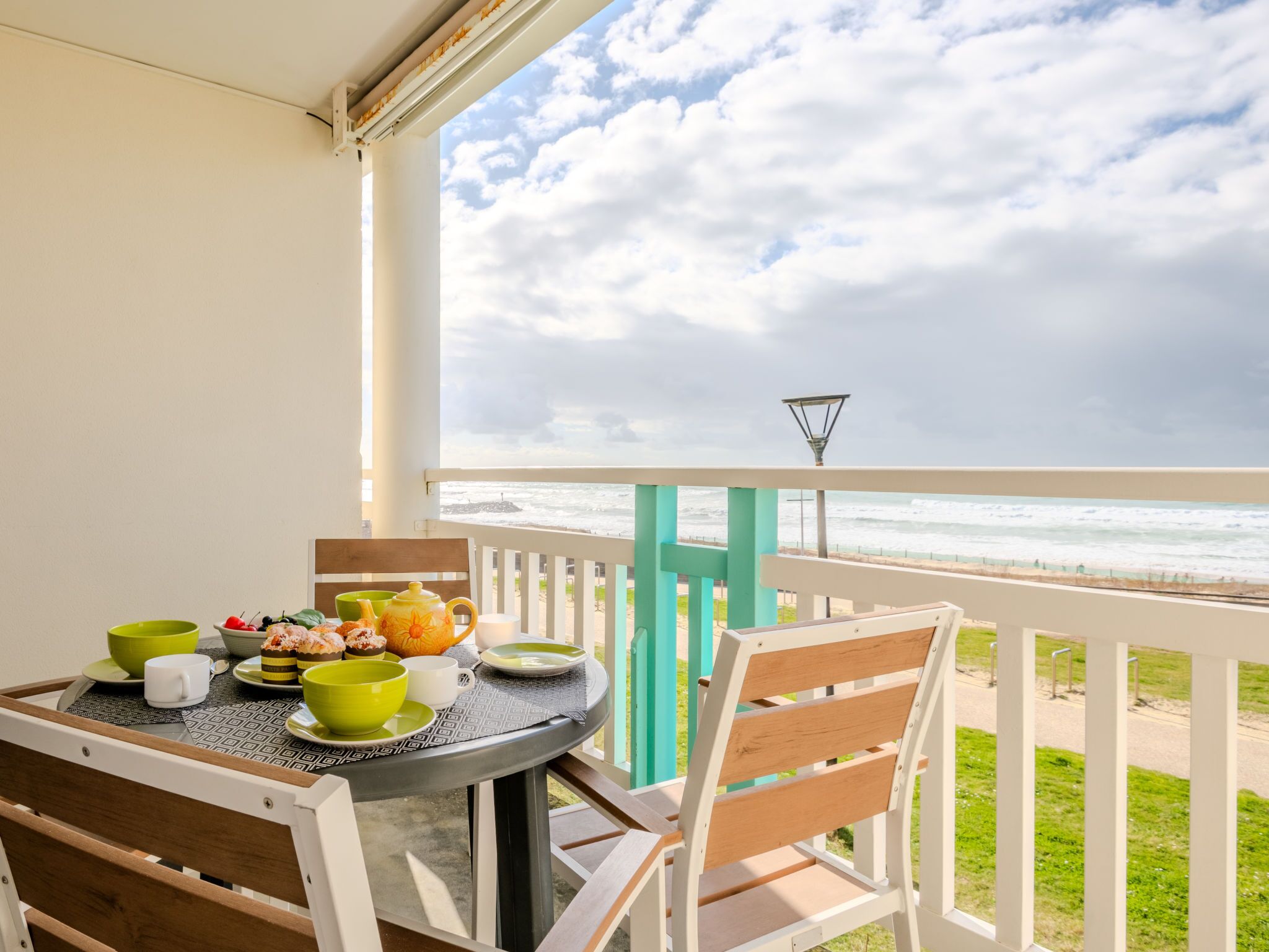 Varanda com mesa posta para o café da manhã, vista para o oceano.