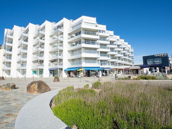Ett modernt hotell med flera våningar, balkonger, en restaurang och uteservering.