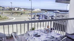 En matplats med ett bord dukat för två personer, med utsikt över en småbåtshamn med båtar och en väg med bilar.