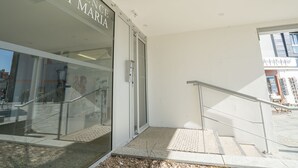 En modern entré till en byggnad med en glasdörr där det står ”RESIDENCE PORT MARIA”.