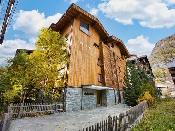 A wooden building with stone accents, labeled "Chalet Rutschji," featuring a stone facade, wooden beams, and a stone entrance.