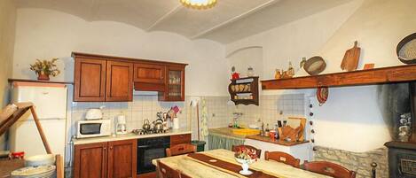 A compact kitchen with wooden cabinets, a dining table, and a stove.
