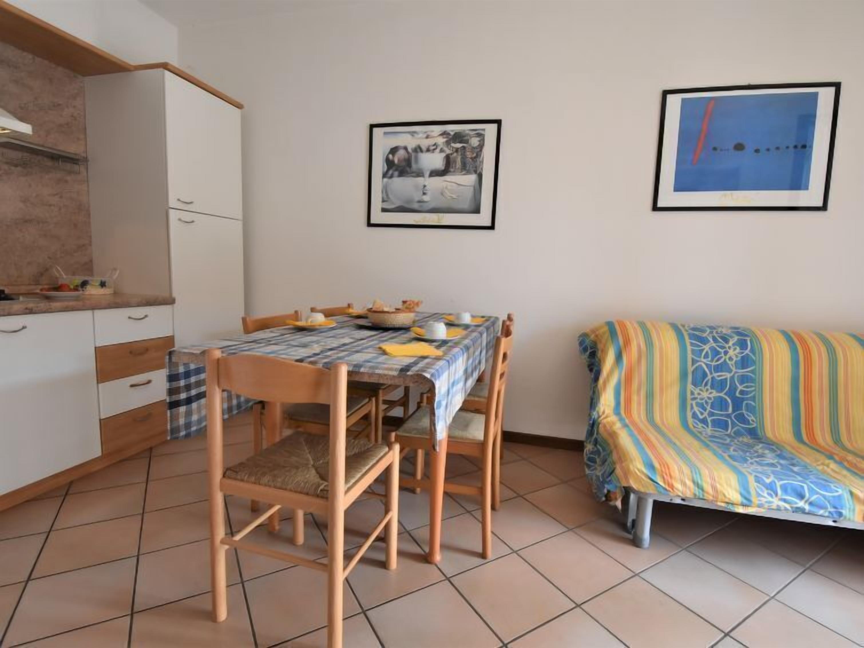 A compact living space with a dining table, chairs, a sofa, and a kitchen area.