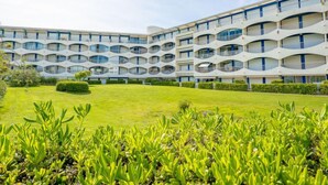 A modern building with a unique curved facade, multiple balconies, and a well-maintained lawn. - Les Terrasses de la Mer by Interhome (La Grande Motte)