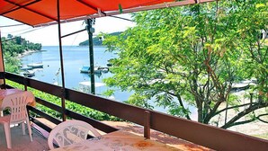 Un balcón con mesa y sillas, con vista a un cuerpo de agua con barcos.