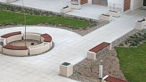Une cour avec un espace de repos circulaire, des jardinières et une pelouse.