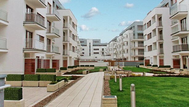 Un immeuble d’appartements moderne, doté de plusieurs étages, de balcons et d’un chemin central.