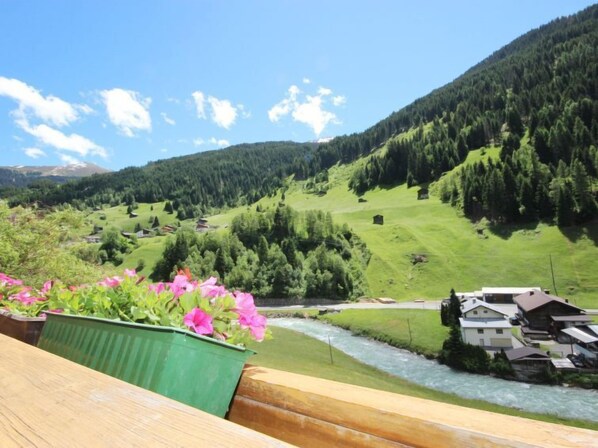 A river flowing through a valley with houses on the right side.