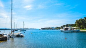 Una marina amb diverses embarcacions amarrades, aigua tranquil·la i cel serè.