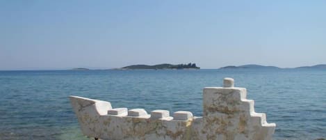 A white ship sculpture on a rock by the sea.