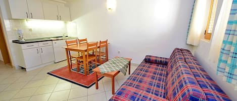 A compact living space with a kitchenette, a dining table with chairs, and a sofa.