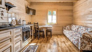 A compact wooden cabin with a kitchenette, a dining table, and a sofa. - Plitvice II by Interhome (Plitvice)
