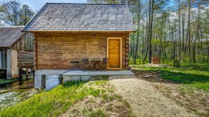 A wooden cabin with a tiled roof, a wooden door, and a small porch with two chairs and a table. - Plitvice II by Interhome (Plitvice)