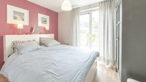 Un dormitorio con cama, dos mesitas de noche, ventana con cortinas y vistas al exterior.