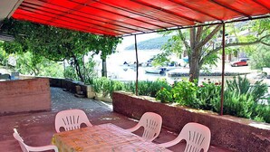 An outdoor patio with a table and chairs, a red canopy, and a view of boats on a lake.