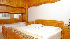 A bedroom with two beds, wooden headboards, and built-in wooden cabinets.