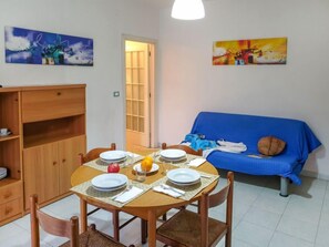 Cozy living space with a dining area, featuring a round table, sofa, and wooden cabinet.