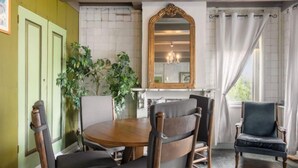 A dining area with a round wooden table, four wooden chairs, a mirror, and a potted plant. - Groepswoning De Appelgaard by Interhome (Zaamslag)